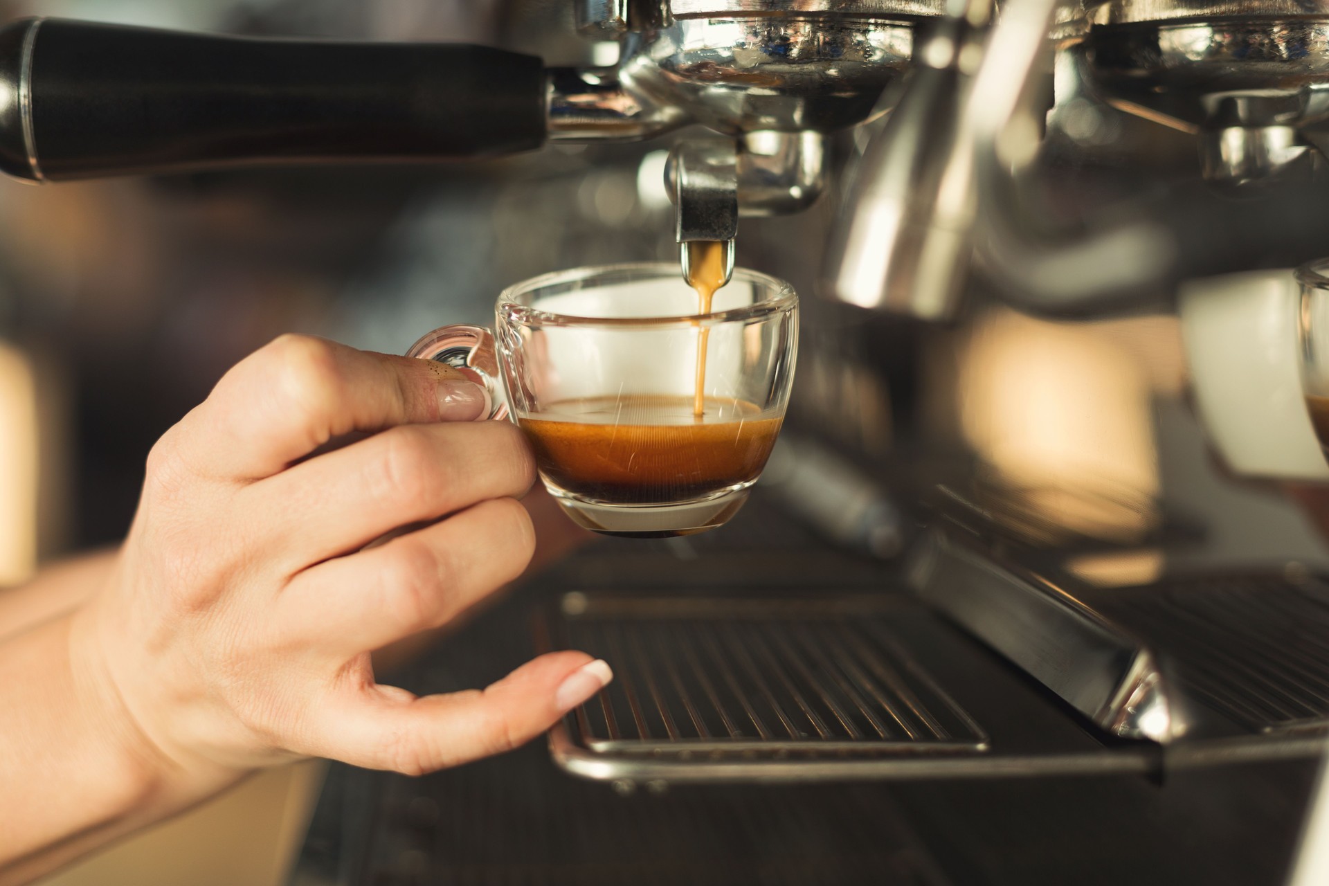 Primo piano di barman che producono a mano l'espresso in una macchina da caffè professionale